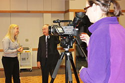 Photo of a student working a camera during an interview. 